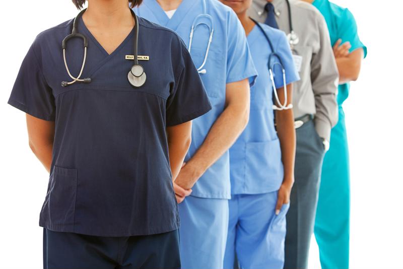 Medical staff wearing scrubs and stethoscopes standing in a line. 